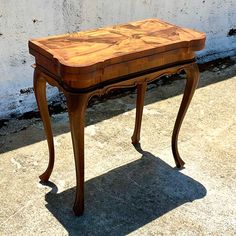 a small wooden table sitting on top of a cement floor next to a white wall