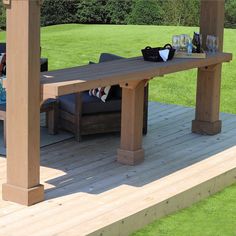 a wooden table sitting on top of a wooden deck next to a green grass covered field