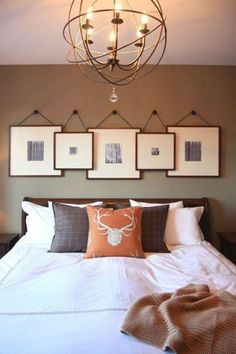 a bed with four framed pictures on the wall above it and a chandelier hanging from the ceiling