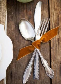 silverware and utensils are laid out on a wooden table with napkins