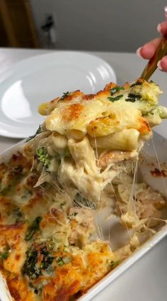 a person holding a piece of lasagna with broccoli and cheese