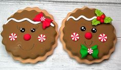 two decorated cookies sitting on top of a white wooden table with red and green decorations