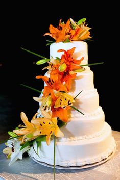 a white wedding cake with orange flowers on top