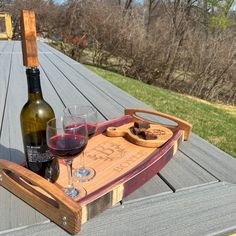 a bottle of wine sitting on top of a wooden tray next to a glass of wine