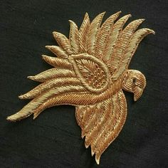 a gold colored bird brooch on a black shirt with an intricate design in the center