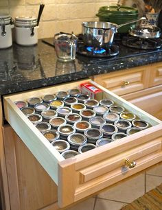 an open drawer in the middle of a kitchen counter with spices and other cooking utensils on it