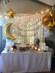 a table topped with balloons and desserts next to a curtained window filled with stars