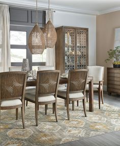 the dining room table is set with beige chairs and wicker baskets hanging from the ceiling