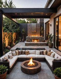 an outdoor living area with a fire pit and couches in the center, surrounded by potted plants