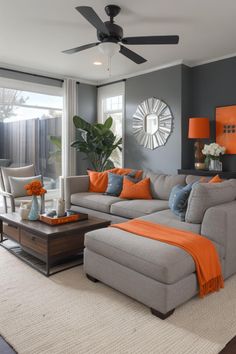 a living room with gray couches and orange pillows