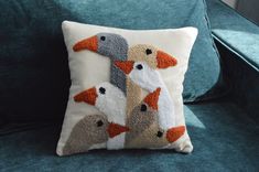 a pillow with two geese on it sitting on a couch