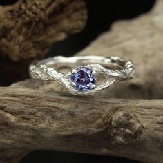 a silver ring with a blue stone in the center on top of a tree branch