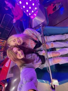 two girls standing next to each other in front of a neon sign and some lights