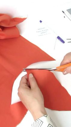 someone cutting fabric with scissors on a table