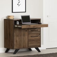 a laptop computer sitting on top of a wooden desk next to a white door and rug