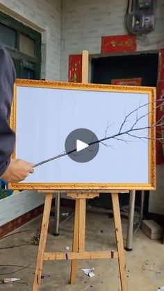 a man is holding a stick in front of a painting