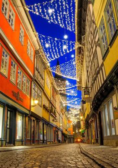 an empty street is lit up with christmas lights