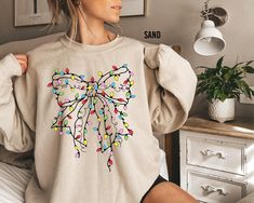 Christmas Light Coquette Bow Sweatshirt, Christmas Sweatshirt, Christmas Light Tee, Christmas Season Shirts, Holiday Sweater, Christmas Gift Thank you for shopping with us❤️ Size - Our products are unisex fit - You can check our size and color charts on our listing photos. How To Order - Select a size - Select a t-shirt color - If available, indicate the design (text) color in the personalization box - Click add to cart. You can go back to add more shirts. - Click "Proceed to check out". Care Instruction -Machine wash in cold water -Do not use bleach -Tumble dry low -Inside out, wash with delicate cycle -Do not iron directly over design Production and Shipping - Processing is 1-3 days * Shipping Time is depending on the shipping option that you choose during to checkout process - Please co Light Coquette, Bow Sweatshirt, Christmas Coquette, Light Girls, Bow Sweater, Design Text, Sweater Christmas, Coquette Bow, Sweatshirt Christmas