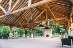 the inside of a wooden structure with chairs and tables in it, surrounded by trees