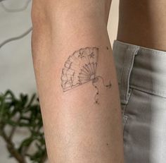 a woman's arm with a tattoo on it and a small fan in the middle