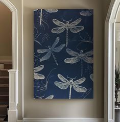 a blue and white dragonfly painting hanging on a wall in a living room next to stairs