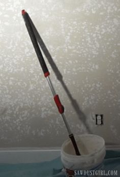 a bucket with two red and black brushes in it on top of a blue table cloth