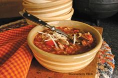 a bowl of soup is sitting on a wooden board with a knife and napkin next to it