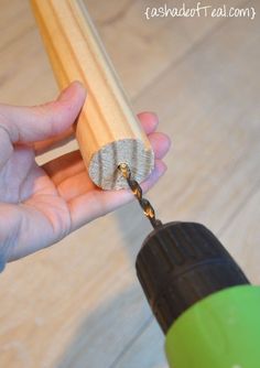 a person is holding a drill and drilling holes in the wooden dows with a green screwdriver