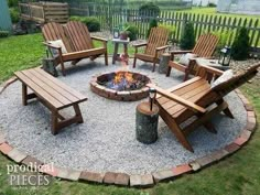 a fire pit surrounded by wooden chairs and tables in the middle of a yard with gravel around it