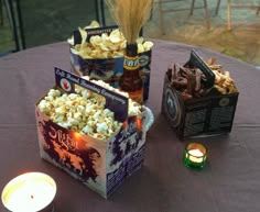 a table topped with two boxes filled with popcorn next to a lit tea light candle