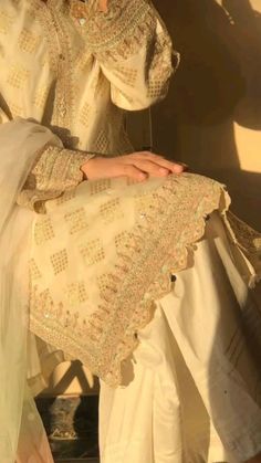 a woman in white is sitting on a chair with her hand over her face and wearing a dress