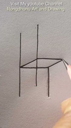 someone is drawing a chair on the wall with black pencils and then it's upside down