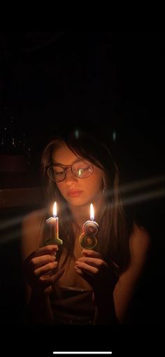 a woman holding two candles in her hands