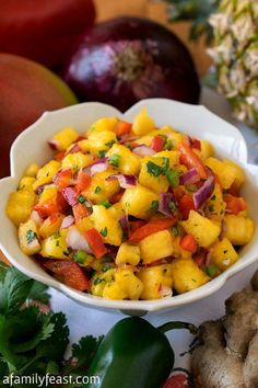 a white bowl filled with pineapple salsa on top of a table next to fruit