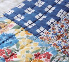 the blue and white flowered quilt is laying on top of the tablecloths