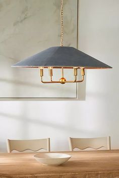 a dining room table with a bowl on it and a light fixture hanging from the ceiling