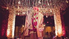 a bride and groom standing in front of a decorated stage