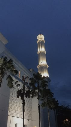 a tall white building with a clock on it's side and palm trees in the foreground