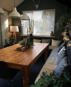 a wooden table sitting in the middle of a living room with lots of plants on top of it