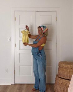 a woman in overalls holding up a yellow shirt