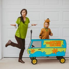 a woman and child dressed up as scooby and the mystery machine in front of a garage