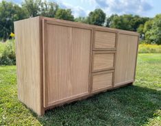 a wooden cabinet sitting on top of a lush green field