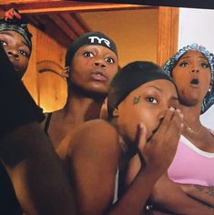 four black women are standing in front of a mirror and one is covering her mouth