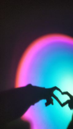 two hands are touching each other in front of a colorful light