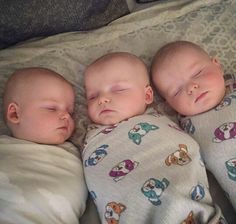 three baby babies sleeping on top of each other