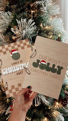 two wooden christmas cards with the words our holly and jolly written on them in front of a christmas tree