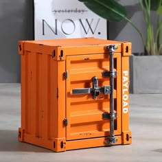 an orange box sitting on top of a table next to a potted green plant