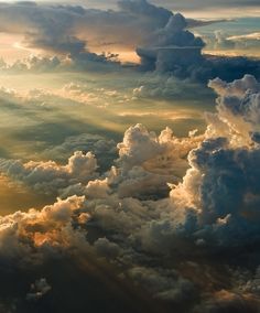 the sky is filled with lots of clouds and sun rays coming through them, as seen from an airplane window