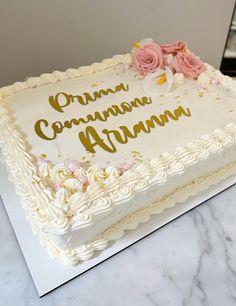 a cake with white frosting and pink flowers on it sitting on top of a table