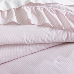 pink and white striped bedding with ruffles on the bottom, along with two pillows